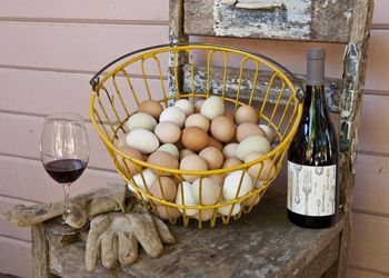 A rustic still life of freshly gathered eggs, garden gloves and a bottle of Big Table Farm wine.