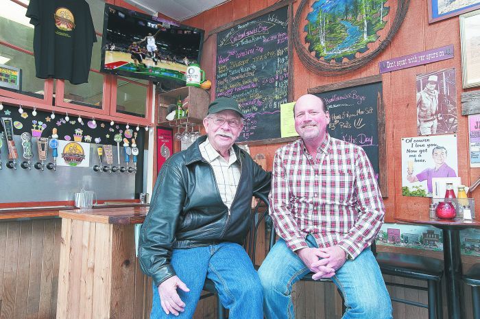Carlton Corners’ founder Vince Larson (left) and his son, Mike, inside the town’s only gas station and growler pub — beer selections change regularly.