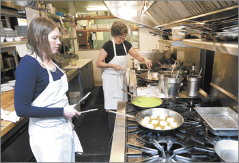 Tina&rsquo;s co-owner Tina Bergen, background,
and chef Abby McManigle prepare the scallop entr&eacute;e for the Dundee restaurant&rsquo;s 20th
anniversary media luncheon. 