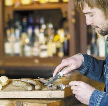 Writer Mark Stock enjoys a glass of Twin Fir Vineyards Pinot Noir while sampling a few of Nicky Farms&rsquo; sausages at Landmark Saloon in Southeast Portland.
