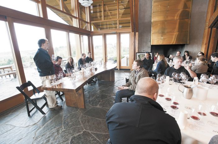 Dick Shea (standing) talks to guests gathered at a comparative tasting event called Tu Shea hosted at Penner-Ash Cellars outside Newberg. (From left) Scott Shull (Raptor Ridge), Lynn Penner-Ash, Stewart Boedecker and Bryan Weil (Alexana) join the discussion and offer their wines made with Shea fruit for the event.