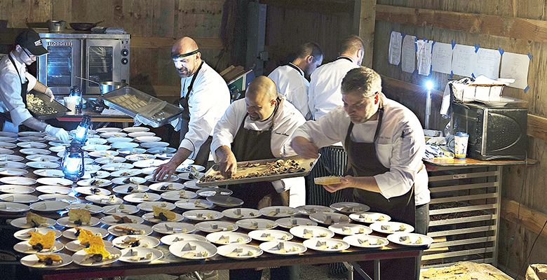 Hunt & Gather crew, led by co-owner/executive chef Andrew Biggs, assembles dishes in a barn at Bergström. Low-light conditions required staff to wear head lamps and light lanterns.